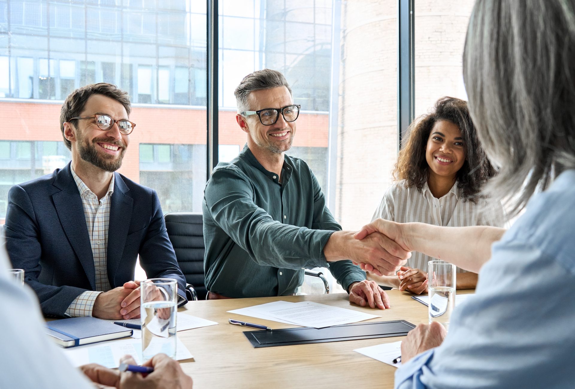 business persons shaking hands at table