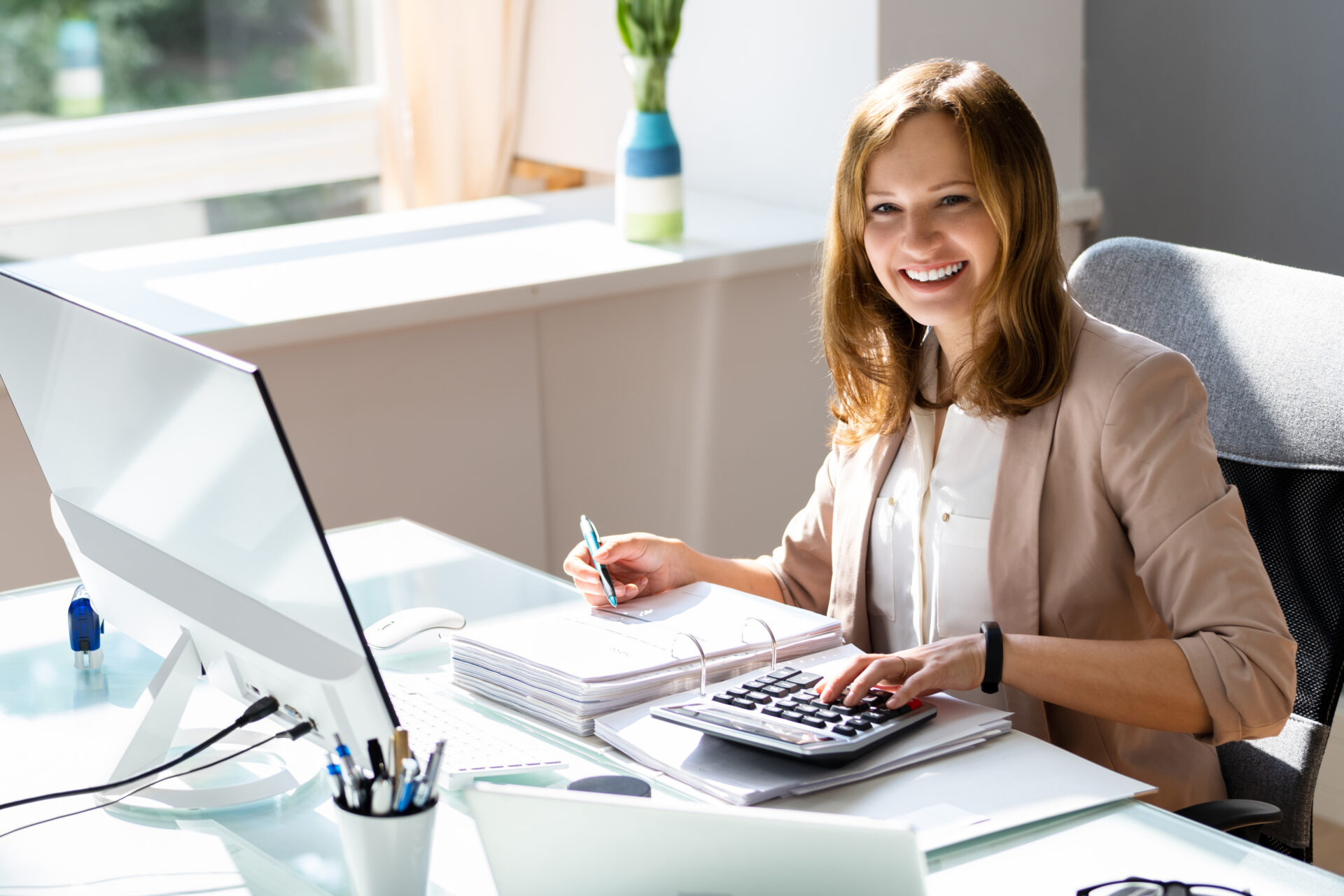 https://www.claytoncartercpa.com/wp-content/uploads/2024/03/Featured-image-woman-at-her-desk-crunching-numbers-and-smiling-at-the-camera.jpeg